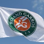 Hvidt flag med French Opens logo med en blå himmel i baggrunden