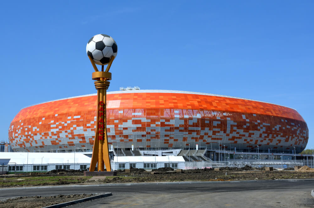 VM-stadionet Mordovia Arena. I forgrunden ses en statue med en fodbold og i baggrunden er stadionet